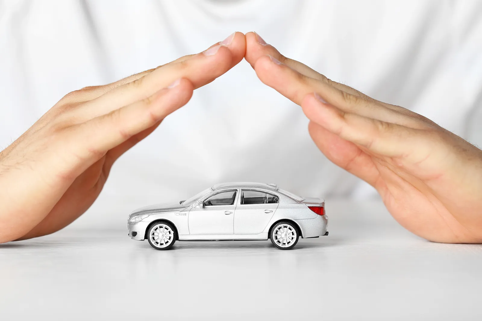 Carro em miniatura protegido por duas mãos